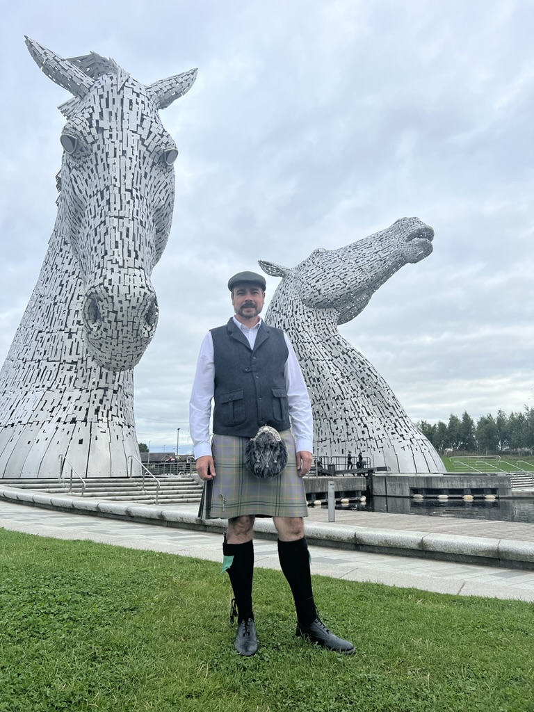 Matty Taylor standing beside the Kelpies sculpture in Falkirk, Scotland